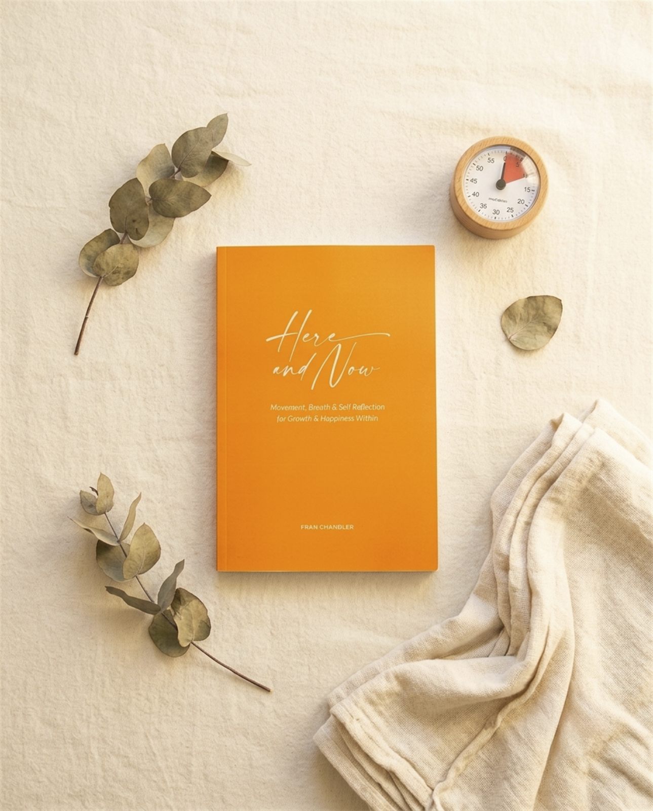 Here and Now styled on linen with dried eucalyptus and a small wooden timer